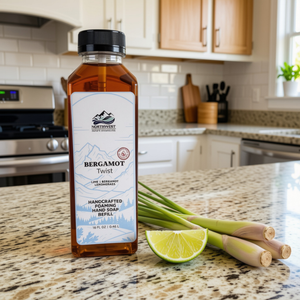 NW Soap Co Bergamot Twist Foaming Soap refill 16 oz square bottle with black lid sitting on counter with wedge of lime and lemongrass next to it
