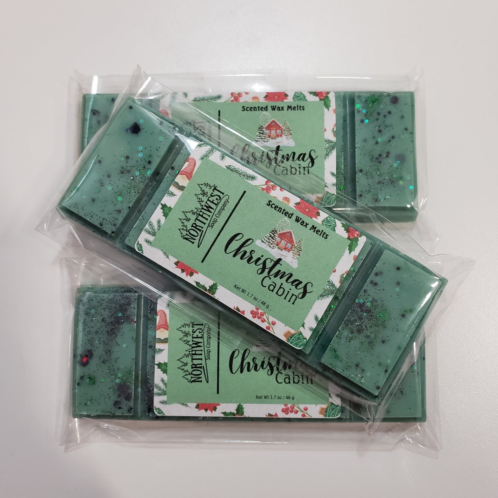 3 Christmas Cabin wax melts packaged in their recylable 5 PP wrappers.  Shaped like a candy bar in dark green with eco glitter.