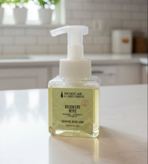 Bottle of Rosemary Mint hand soap on a kitchen counter with plants in the background