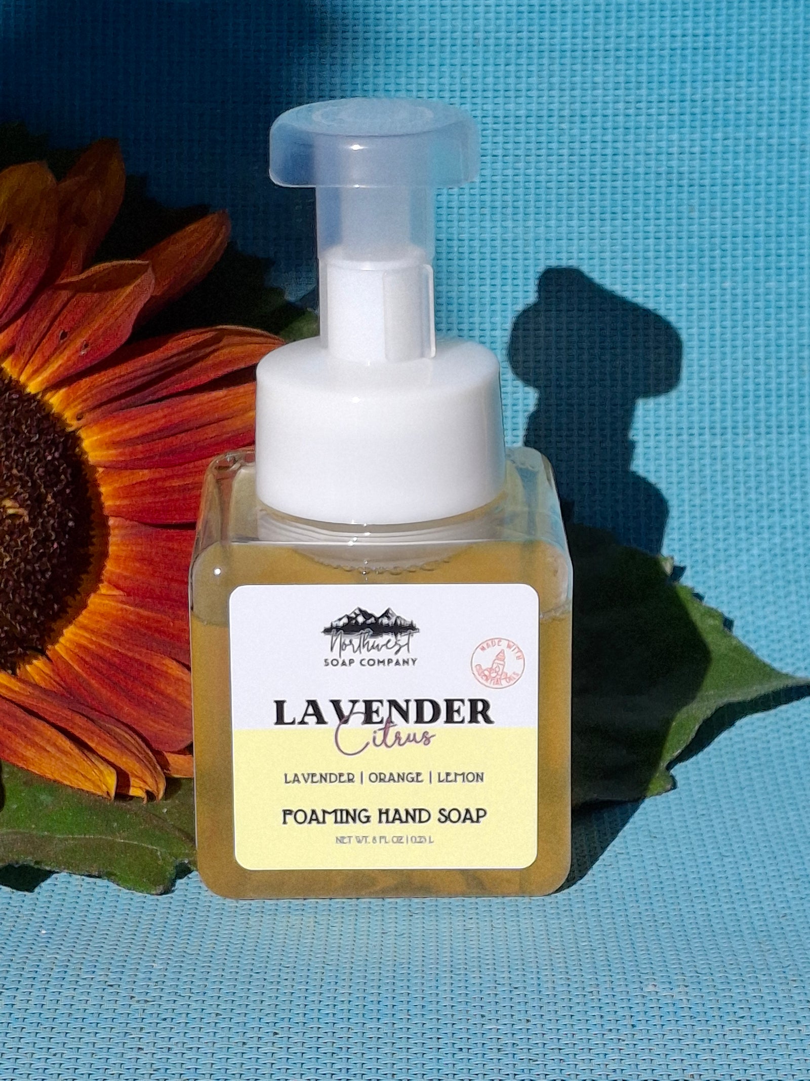 Lavender hand soap bottle with a sunflower on a blue textured background