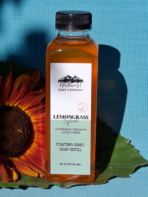 Bottle of Lemongrass Splass hand soap refill with a label on a blue background with a sunflower and leaf.