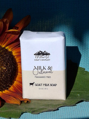 Bar of soap pictured with a sunflower and large green leaf