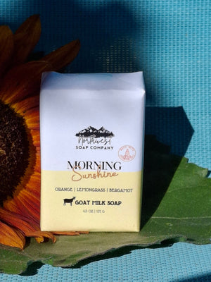 Bar of soap with packaging on a sunflower against a blue background