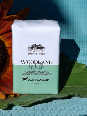 Bar of Woodland Soap Company goat milk soap on a sunflower with a green leaf