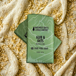 Two green bars of soap from Northwest Soap & Candle Company on a textured fabric background with oats.