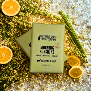 Goat milk soap bar from Northwest Soap & Candle Company with lemons and herbs on a textured surface