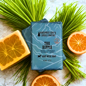 Bar of soap with 'The Hippie' label surrounded by orange slices and green leaves on a light surface.