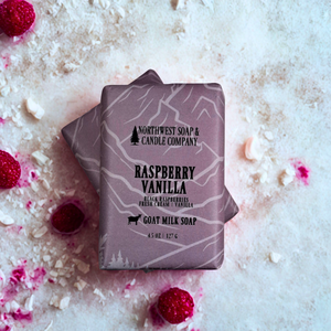 two bars of raspberry vanlla bars of soap on a white background with raspberries and candy crumbles