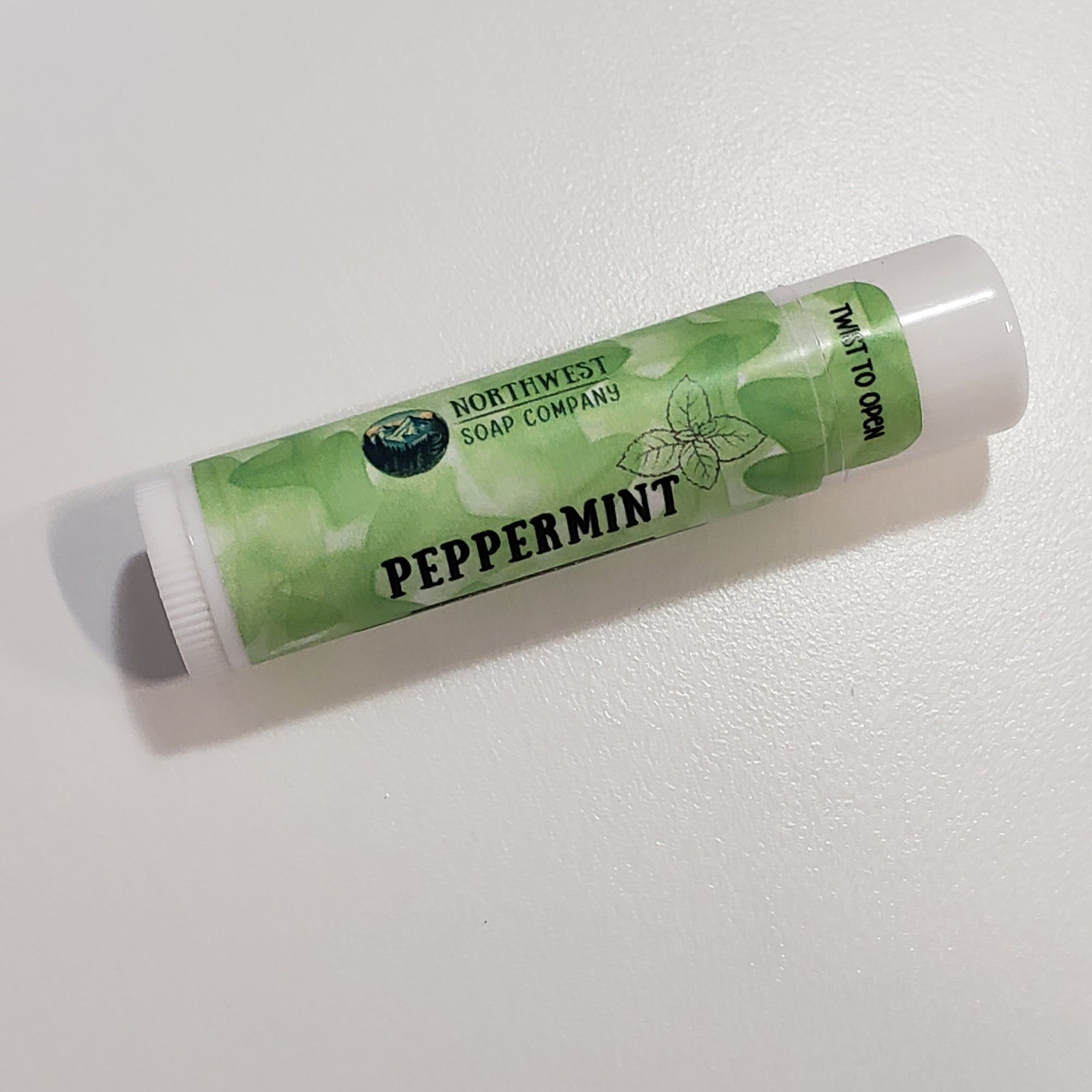 One tube of our Peppermint lip butter with it's white lip balm tube and green label.