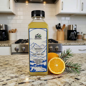 A bottle of Northwest Soap Company Handmade Ocean Storm hand-soaked and foaming hand soap refill, placed on a granite kitchen countertop with a fresh orange and cedar sprigs.